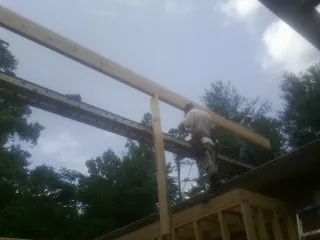 Carpenter setting a ridge beam over a new addition frame — Ice Dam Removal by Roofing Brothers in Bent Mountain