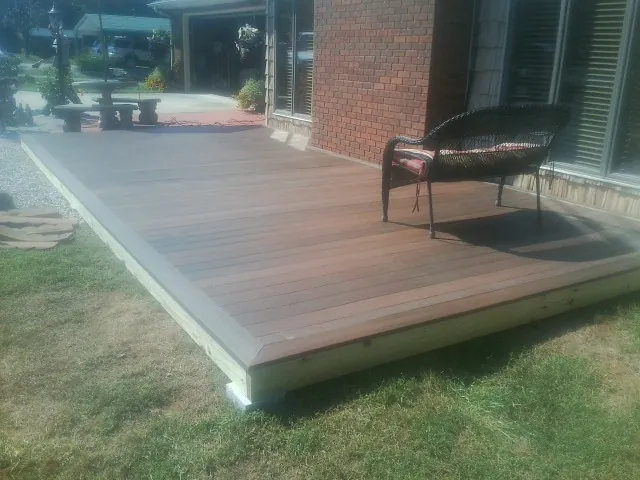 New wood deck and wicker chair beside a brick house in Bent Mountain