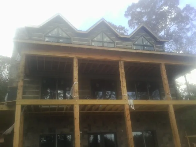 Dormers and porch framing on a large log home under construction — Roof Coating work by our crew in Bent Mountain