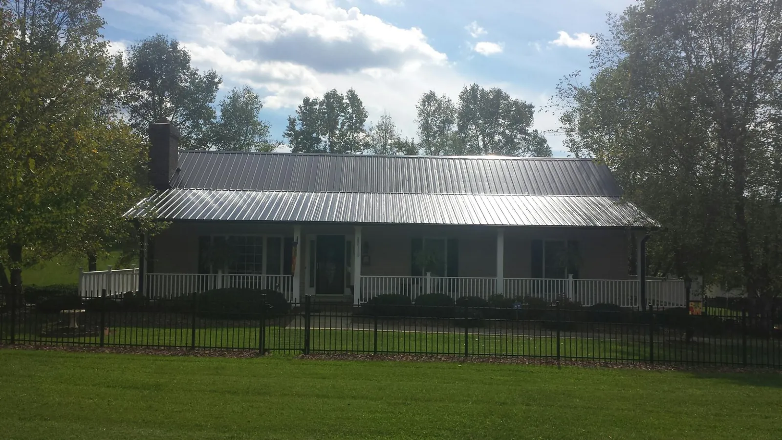 Gray metal roof on a brick ranch with a full width front porch — Gutter Guard Installation work by our crew in Bent Mountain
