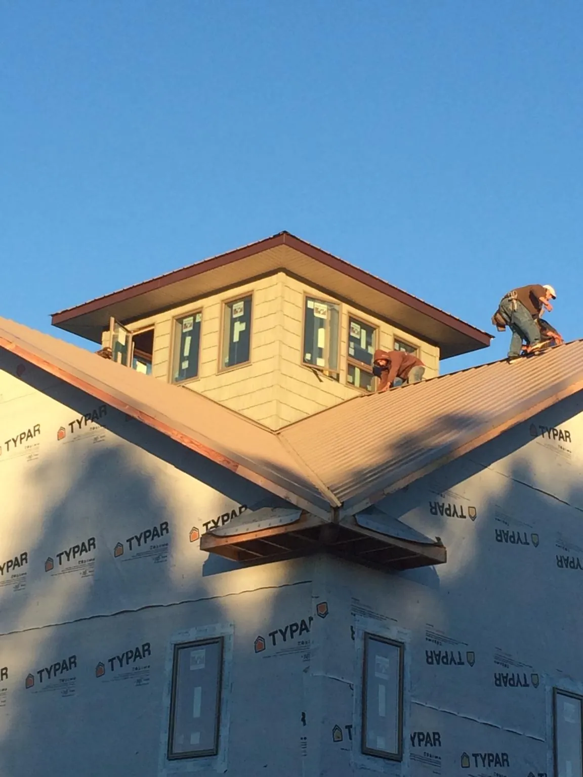 Roofers working around a rooftop cupola on a new metal roof at sunset — Roof Waterproofing in Bent Mountain by Roofing Brothers